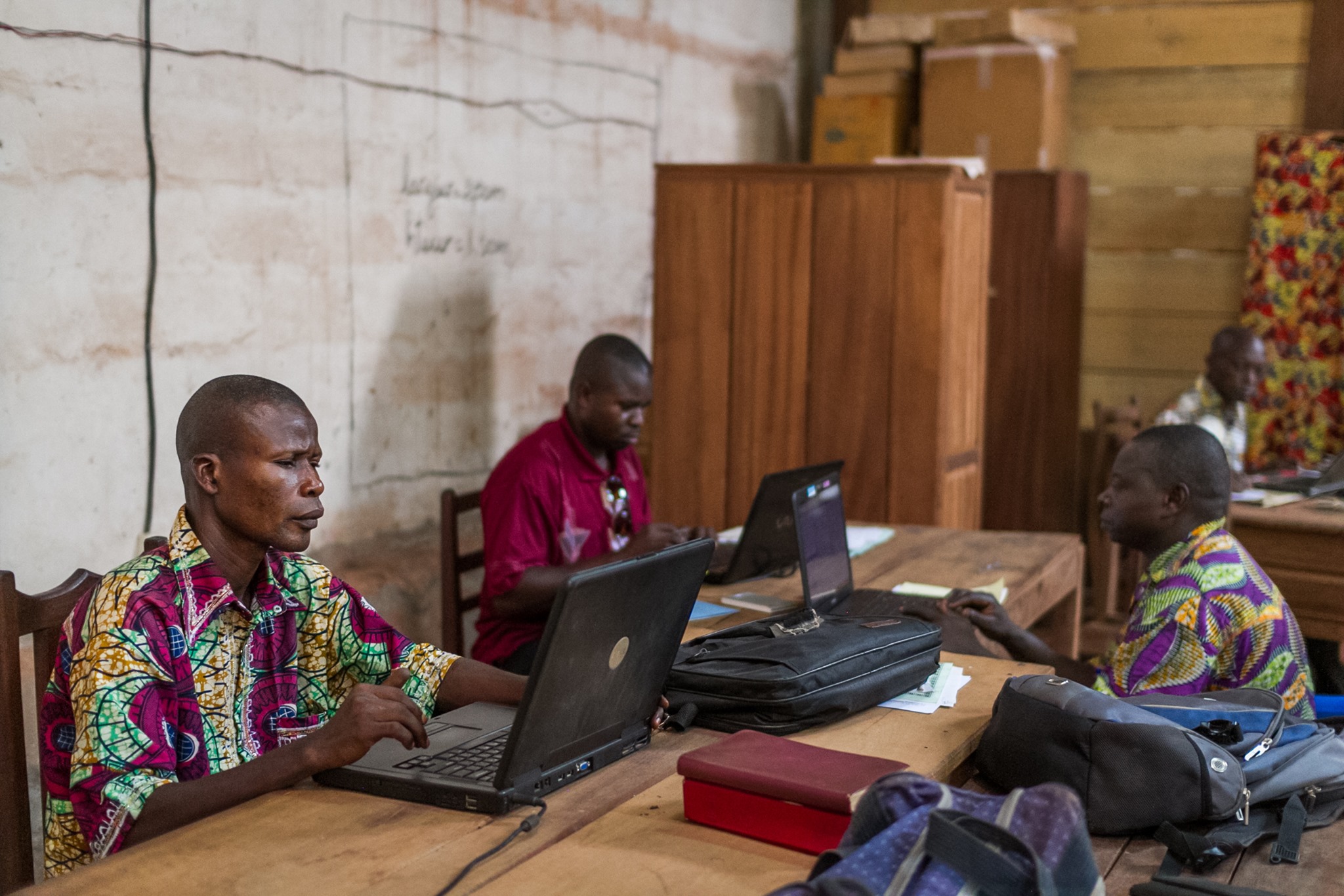 Three men gathered together working on Bible translation