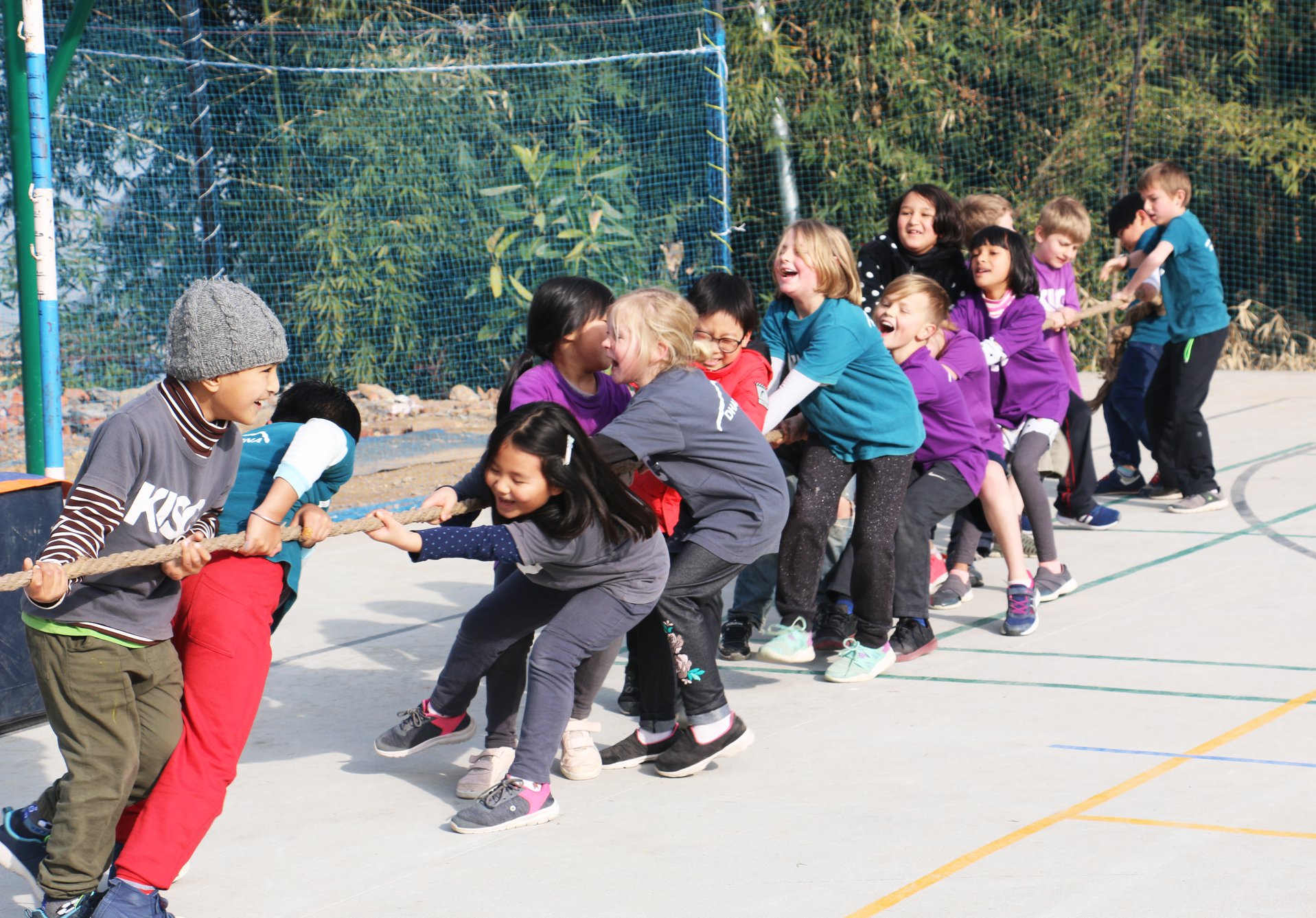 Children in a schoolyard playing tug-of-war