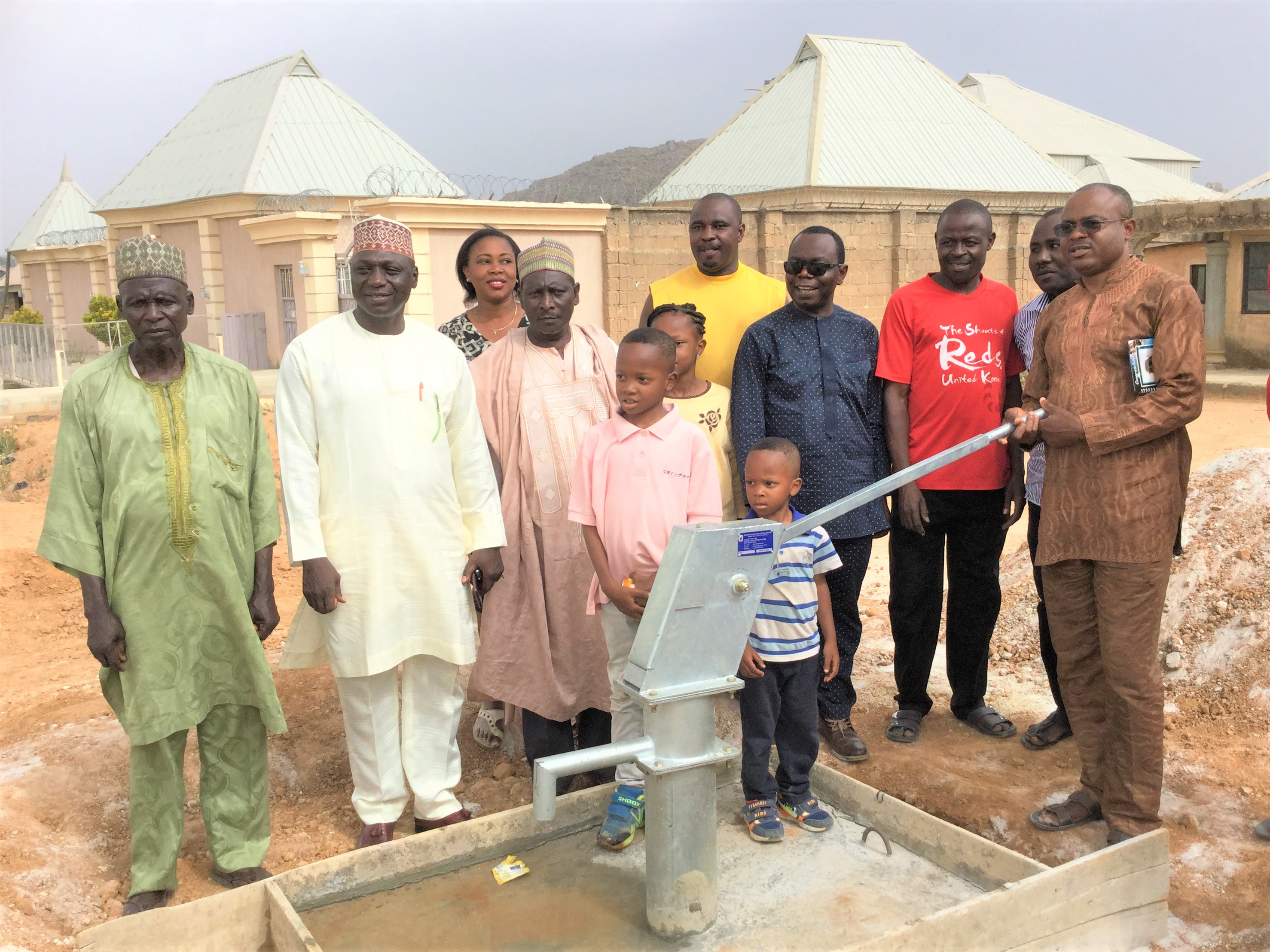 Teachers standing by a community well they installed