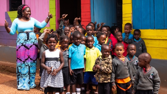 A teacher and her students stand outside of their school