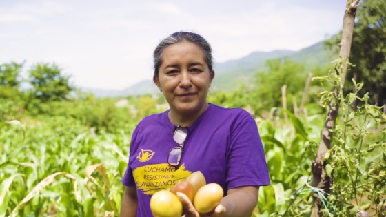 Marta standing in one of her fields and holding crops