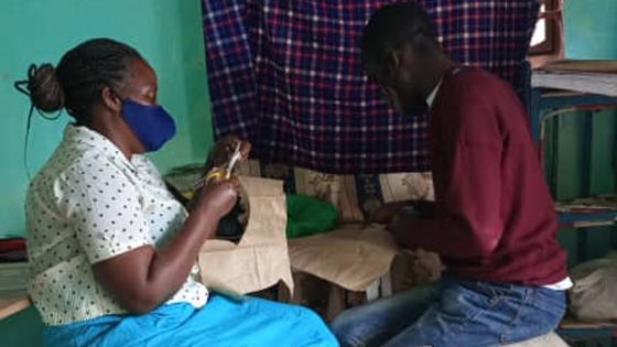 Harriet teaching a young person in her community a craft