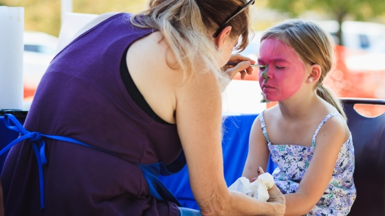 Woman painting a child's face pink