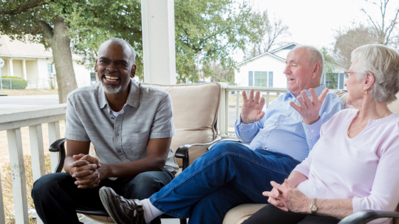 Three people talking and laughing on a porch