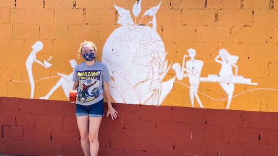 Student stands beside painted wall