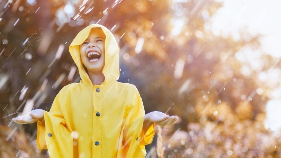 Child wearing a yellow rain jacket smiling in the rain