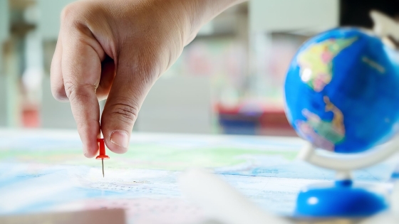 Hand placing a pin in a map