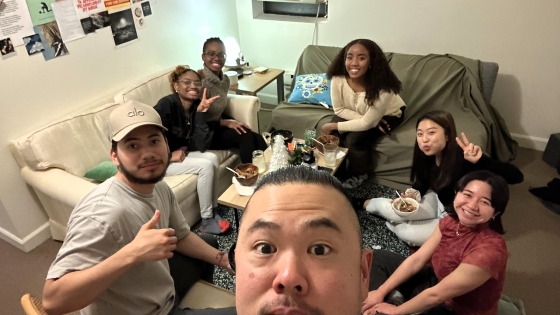 Dennis and a group of students gathered on couches and chairs around a coffee table with snacks