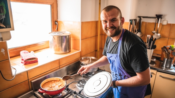 Csaba smiles while cooking in front of a stove