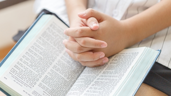 Hands folded on a Bible