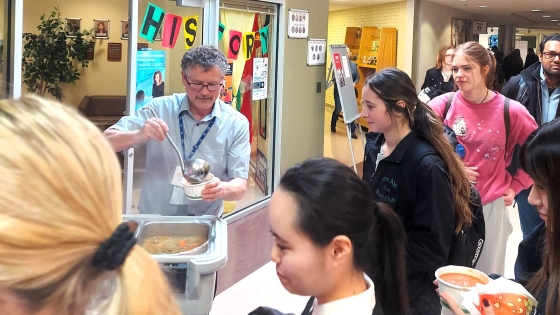 George Koopmans distributes food while students stand in line