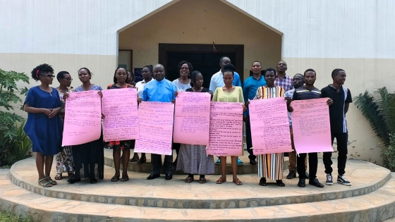 A group of TLT participants stand outside the church holding posters with their Action Plans written out