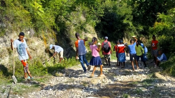 A group of students work on repairing a dirt road in Haiti