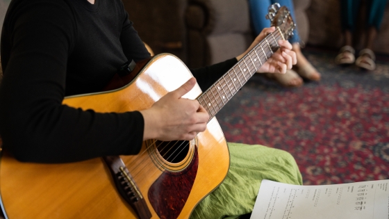 Elena strums a guitar during worship at a Cohort meeting