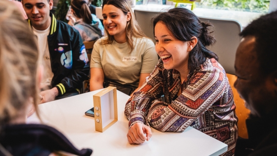 A group of young adults gathered around a table and smiling