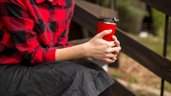 Woman sitting on front steps holding a thermos