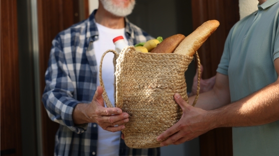 Man handing over bag of groceries to another man