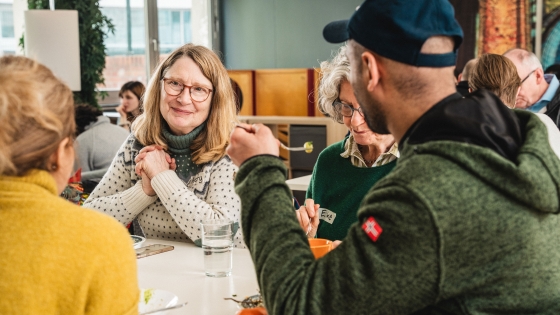 Resonate missionary Mary Buteyn smiles while sitting at a table with two men and a woman