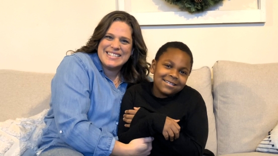 Joan and Elijah sitting on a couch and smiling