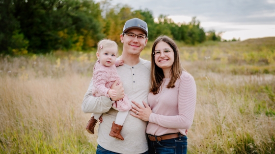 Steven, Ashley, and their daughter in a field