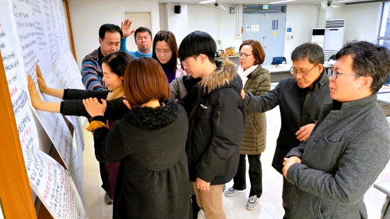 Rev. Kim and a group pray over action plans they created in Timothy Leadership Training