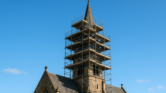 A brick church steeple with scaffolding surrounding it