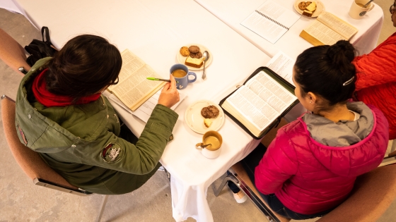 Aerial view of two women sitting at a table with Bibles open