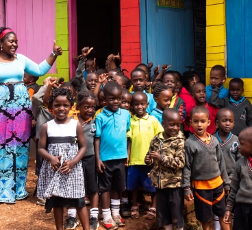 A teacher and her students stand outside of their school