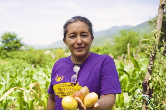 Marta standing in one of her fields and holding crops