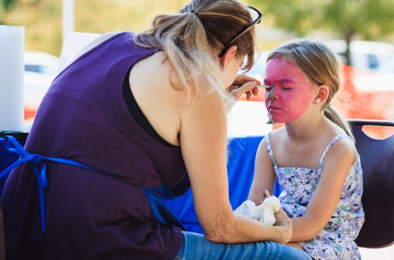 Woman painting a child's face pink