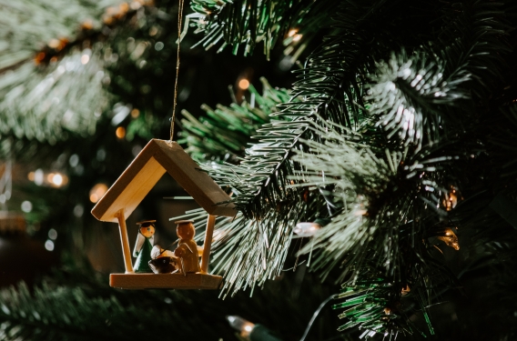 Ornament of nativity scene hanging from a Christmas tree branch