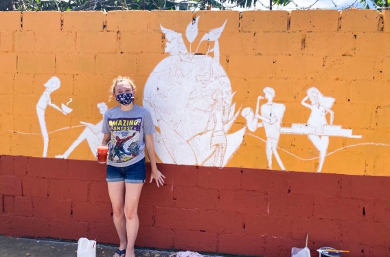 Painting a Wall at Casa Adobe Student stands beside painted wall