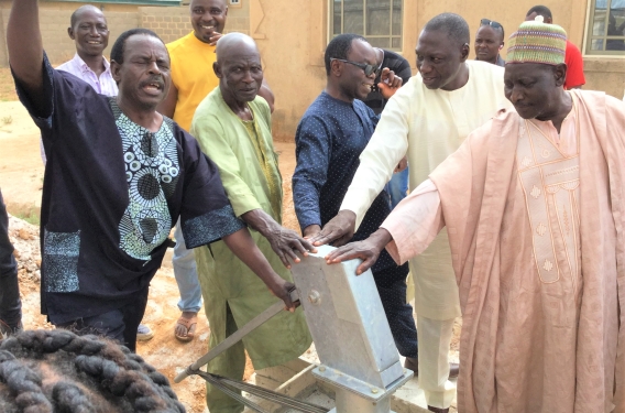 Teachers praying over a community well they installed